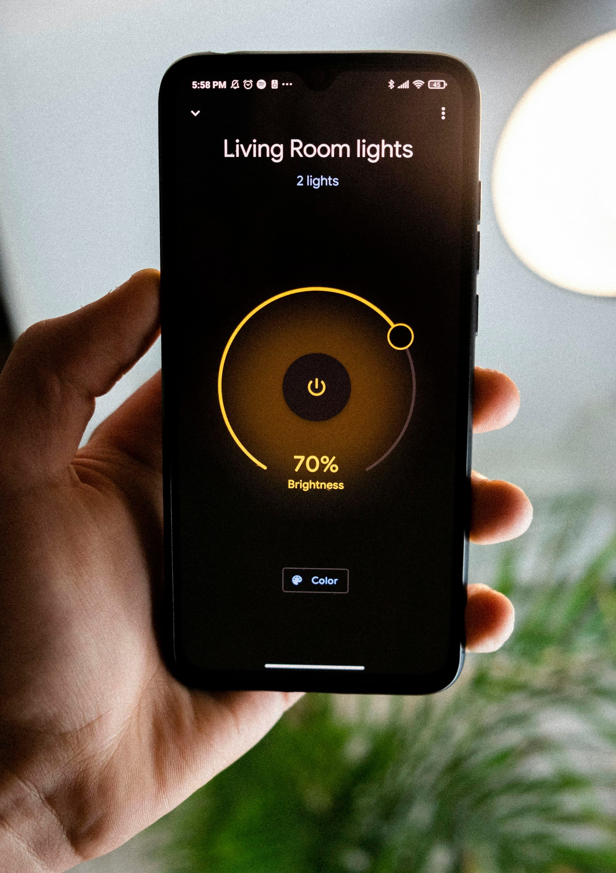 Hand holding a phone with a smart-lighting control app