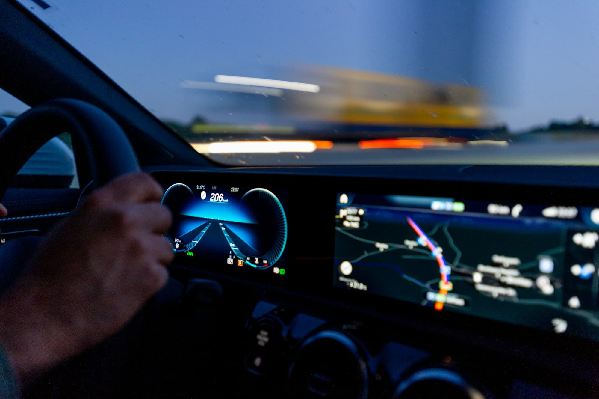 Driver's hand on the steering wheel beside a live map display
