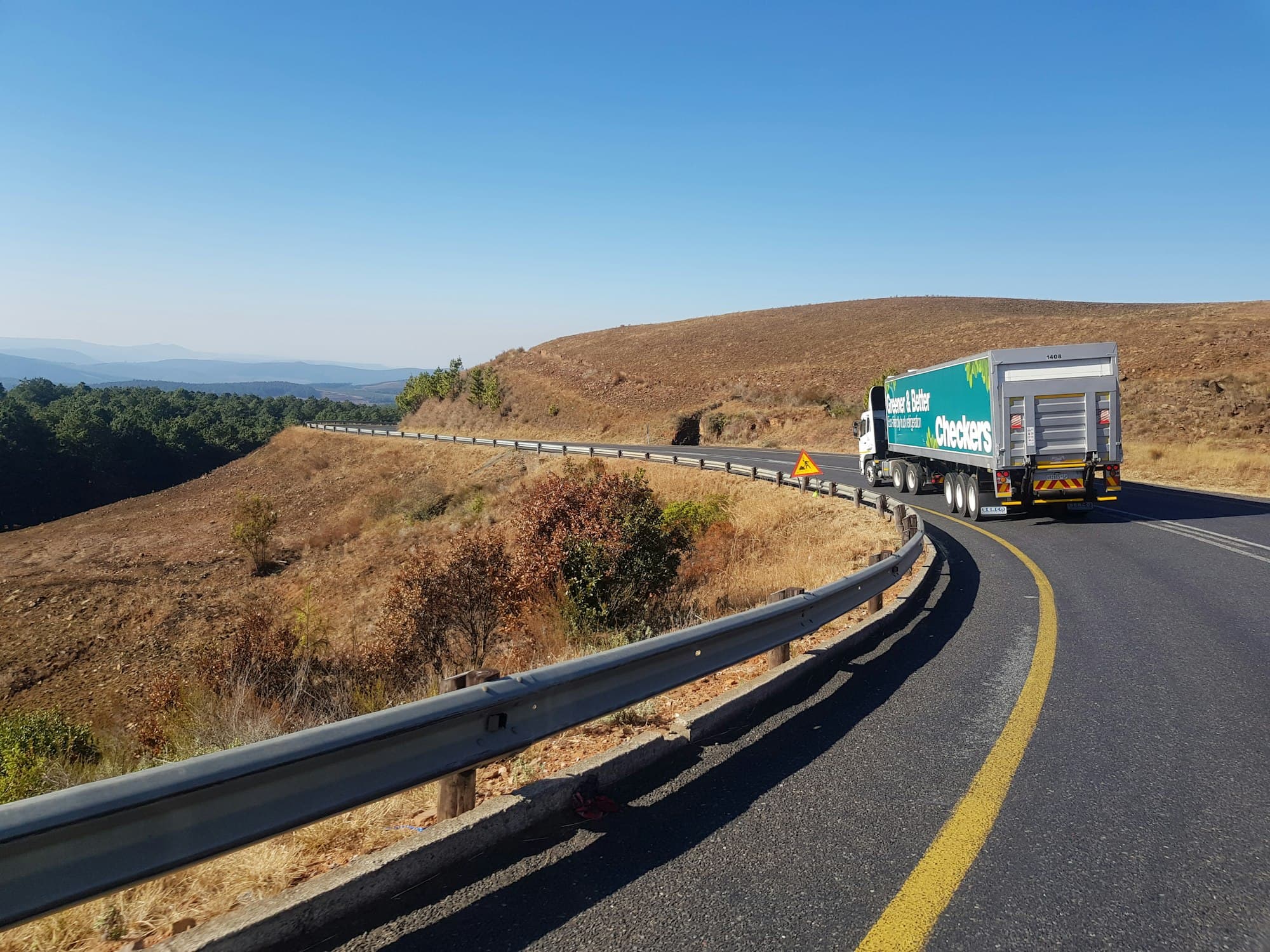 Lorry driving along a winding highway under a clear sky