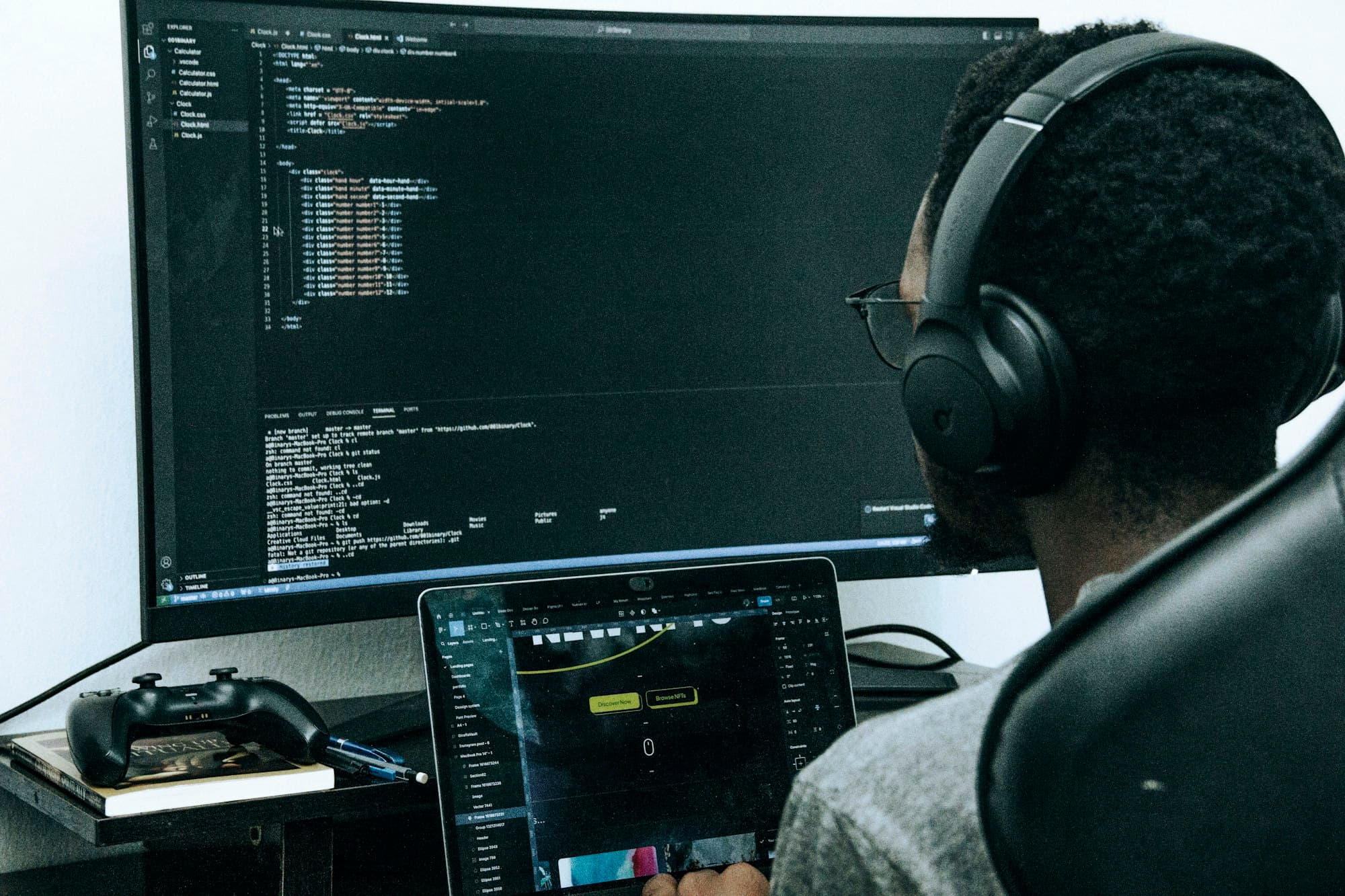 Software developer wearing headphones, working on code across two monitors